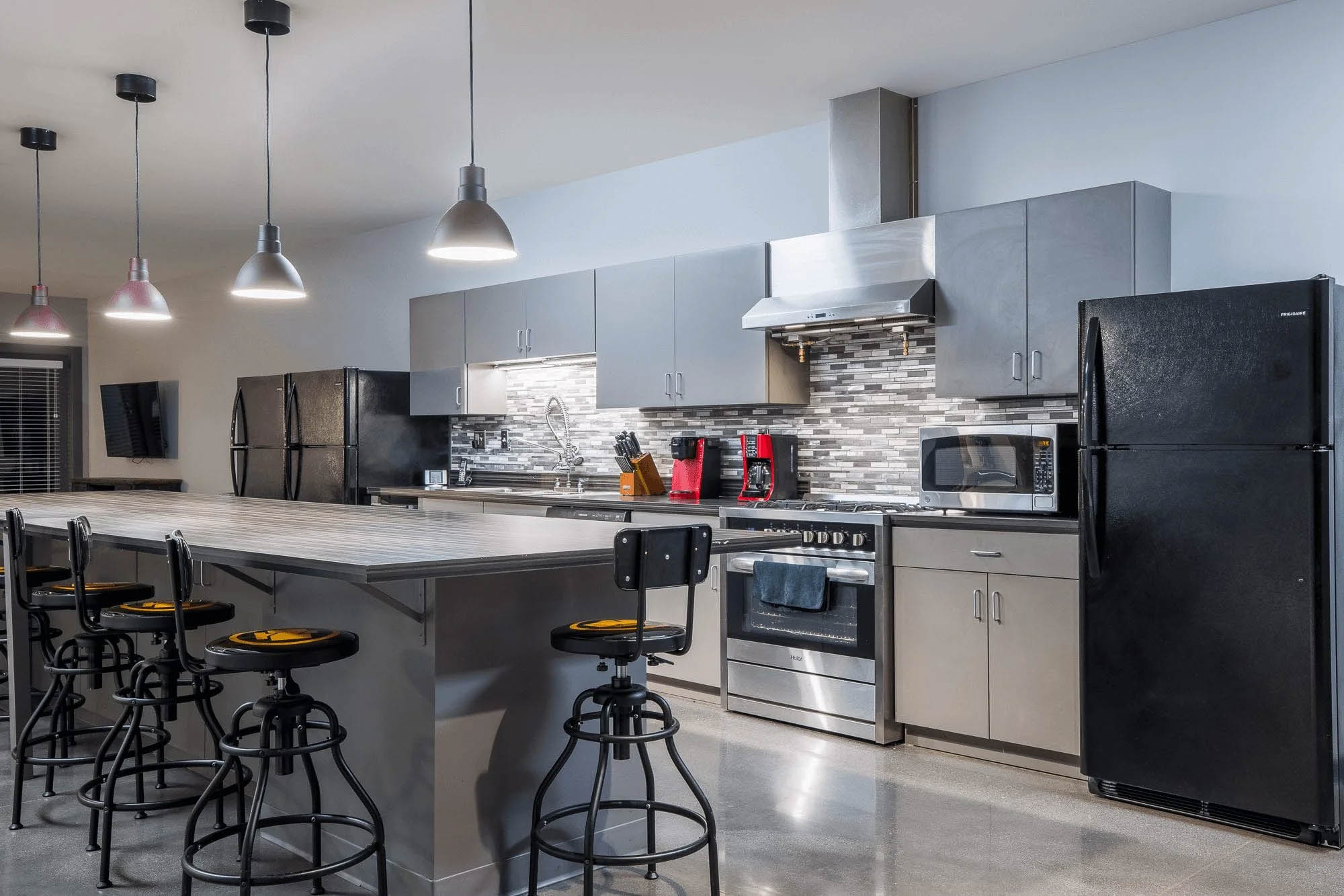 Knoxville architectural photography of a modern commercial kitchen with stainless steel appliances, gray cabinetry, pendant lighting, and a large island