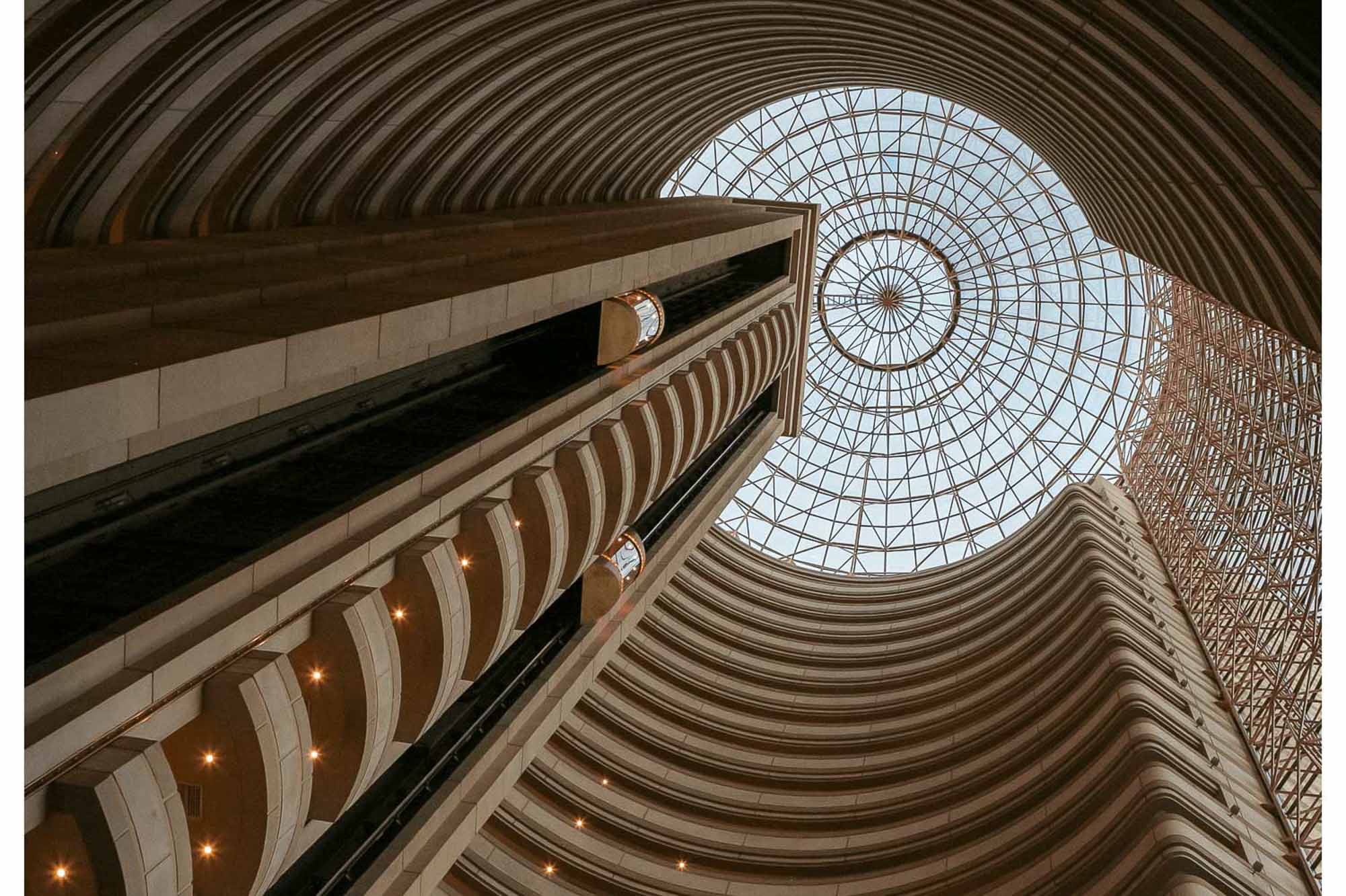 Knoxville architectural photography looking upward through a dramatic multi-story atrium with curved balconies and a geometric glass ceiling
